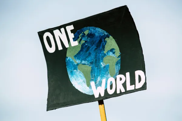 Ein Schild mit dem Ausdruck "One World" wird hochgehalten. 